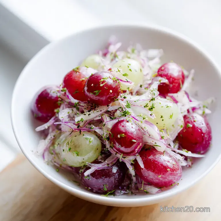 A delicate swirl of creamy grape salad artfully arranged in a crystal bowl, topped with a sprig of mint.