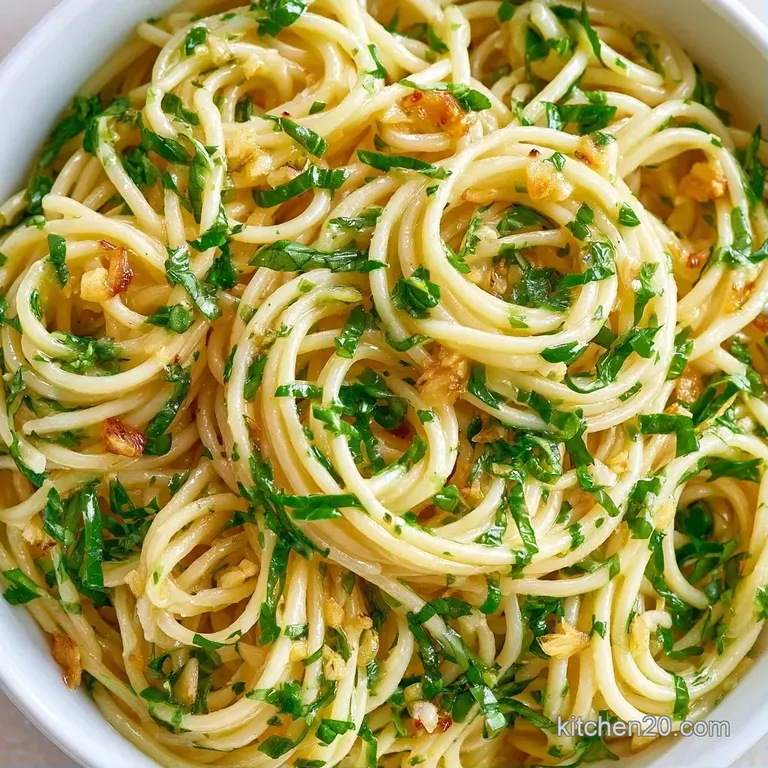 Twirled pasta nests glistening with melted butter and topped with shredded parmesan and vibrant basil sprigs.
