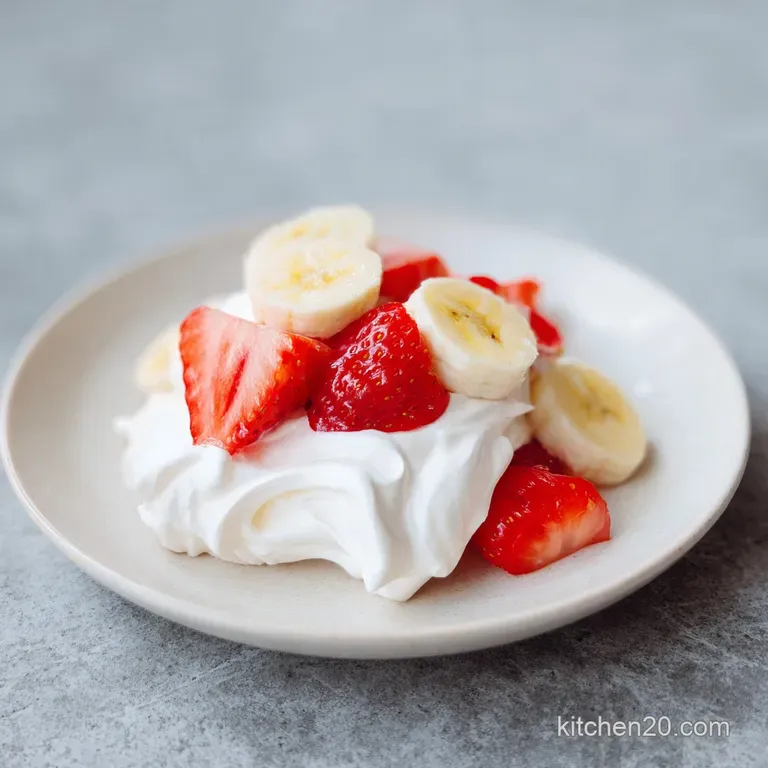 Elegant scoop of airy pink cream topped with fresh strawberry slices and banana in a chilled crystal coupe.